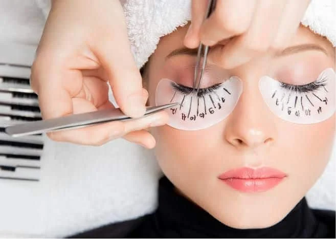 Lash extension training — tweezers and numbered lash map on eye pads